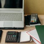 Organized office desk featuring a laptop, calculators, and notebooks for productive work.